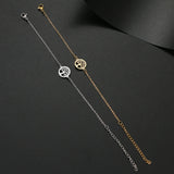 Two gold and silver tree-of-life anklets on a dark surface