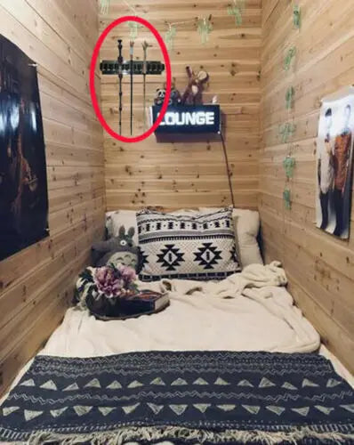 Small bedroom with wooden walls, a bed with patterned bedding, and a 'Lounge' sign on the wall.