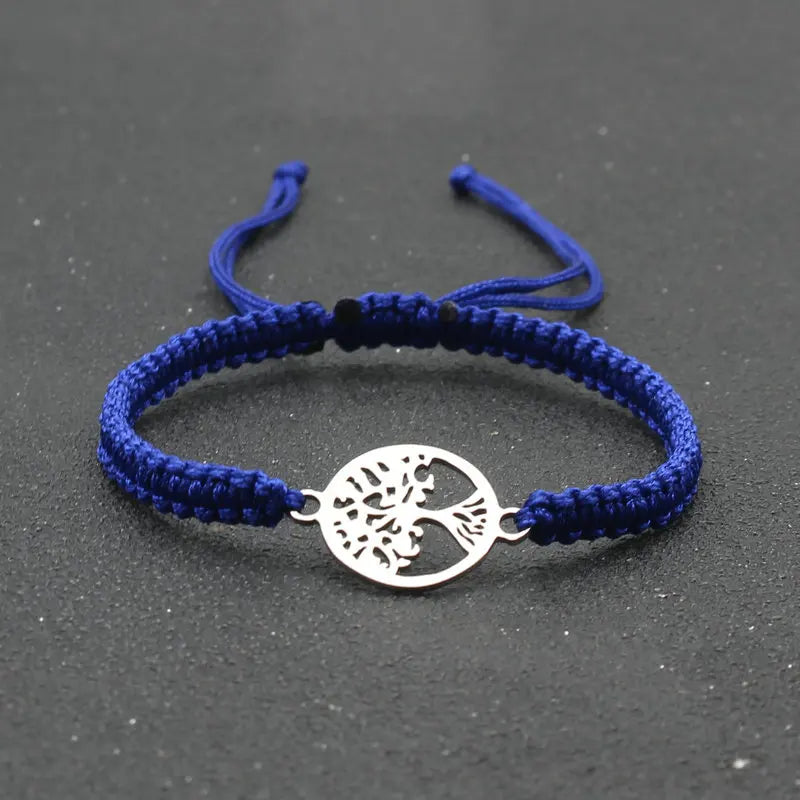 Blue braided bracelet with a silver tree-of-life charm on a dark gray background