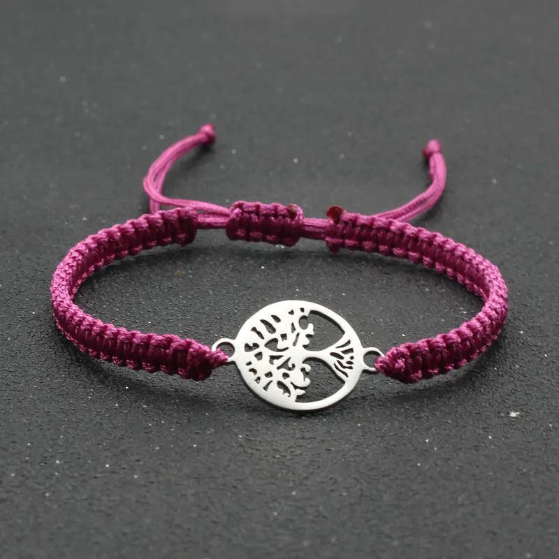 Purple braided bracelet with a silver tree of life charm on a dark background
