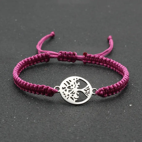 Purple braided bracelet with a silver tree of life charm on a dark background