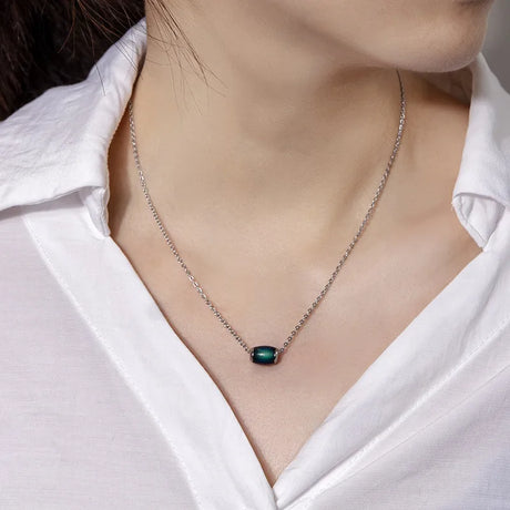 Necklace with a green gemstone worn by a person in a white shirt