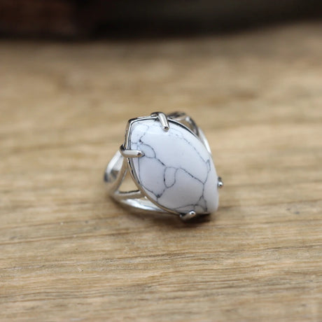 Silver ring with a white stone on a wooden surface