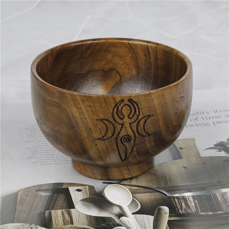 Wooden bowl with engraved design on a surface with text and other items.