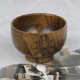 Wooden bowl with engraved design on a surface with text and other items.