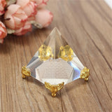 Crystal pyramid with gold accents on a wooden surface