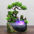 Decorative water fountain with a bonsai tree on a wooden surface