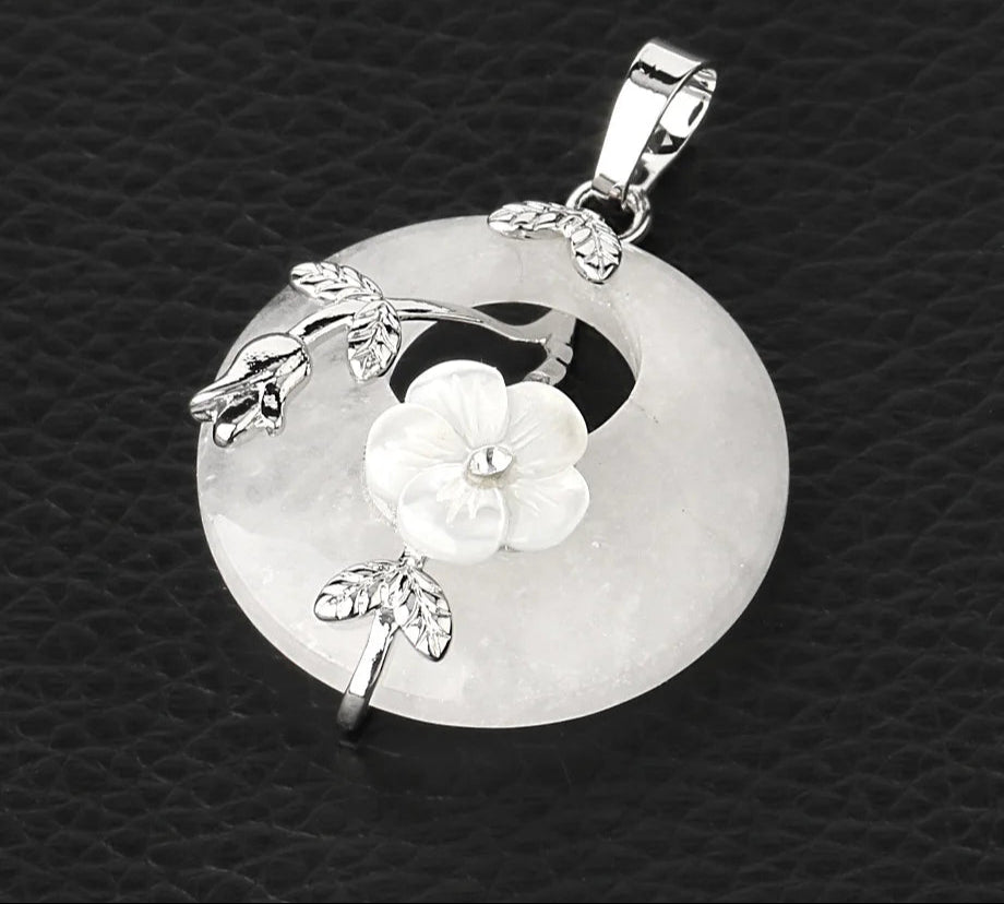 Silver pendant with floral design on a textured black background