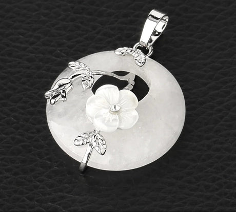 Silver pendant with floral design on a textured black background