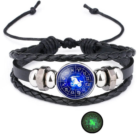Black braided leather bracelet with silver accents and a blue astrological symbol charm on a white background.