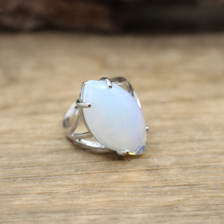 Silver ring with a light blue stone on a wooden surface