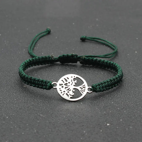 Green braided bracelet with a silver tree of life charm on a dark background