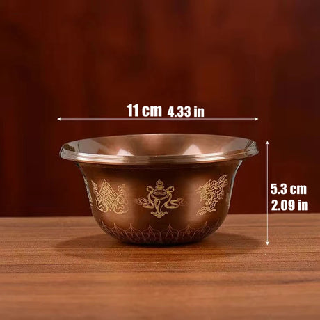 Bronze bowl with engraved designs on a wooden surface, shown with measurements.