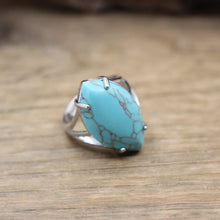 Turquoise ring with silver band on a wooden surface