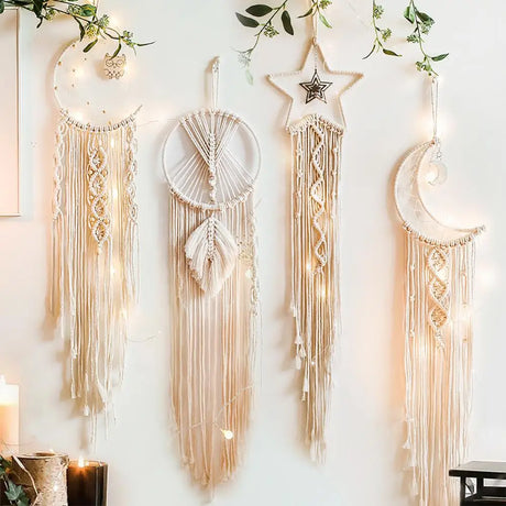 Set of four decorative dreamcatchers hanging on a wall with candles and greenery.