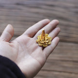 Gold decorative object held in a hand against a wooden background