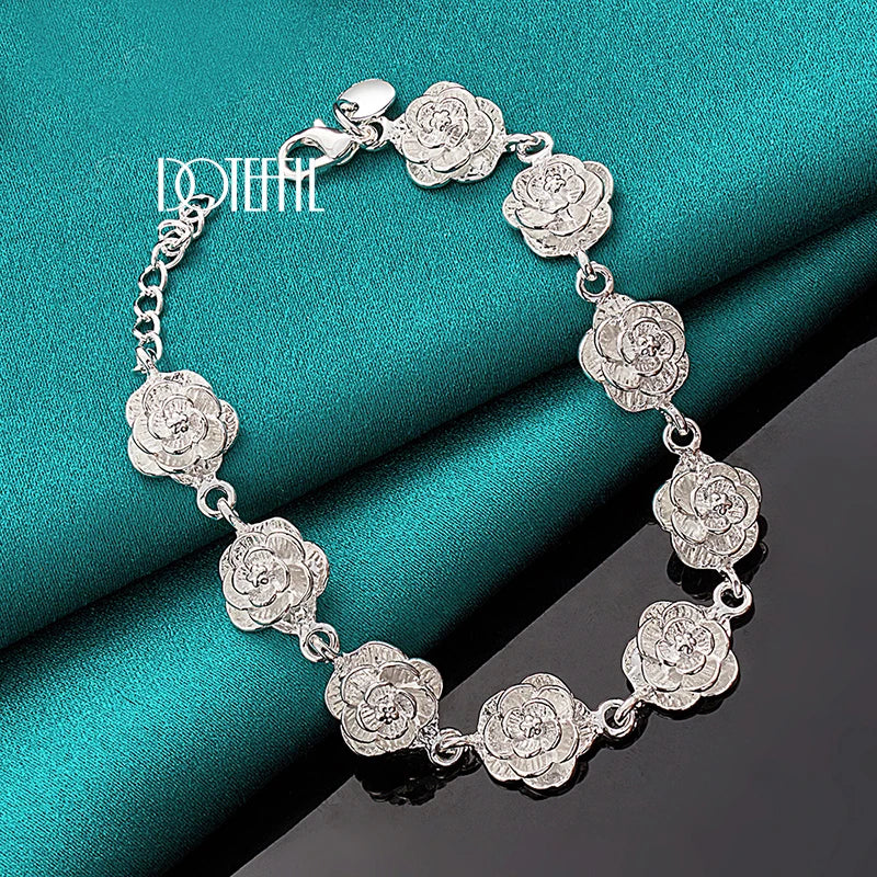 Silver floral bracelet on a teal fabric background