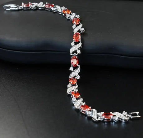 Silver bracelet with red gemstones on a black surface