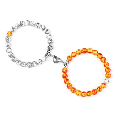 Two bracelets, one silver and one with orange beads, on a white background