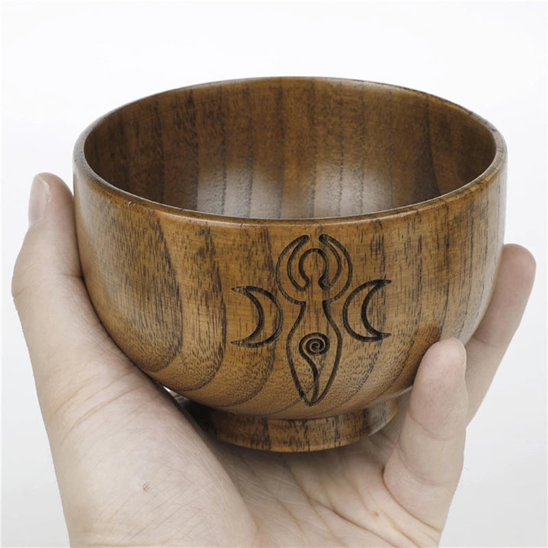 Wooden bowl with engraved symbol held in a hand against a white background