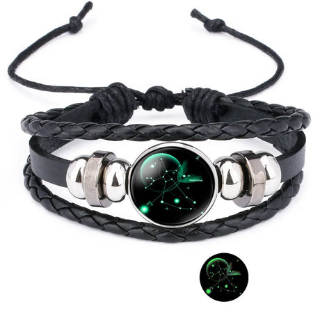 Black braided leather bracelet with silver accents and a glowing green astrological symbol on a white background.