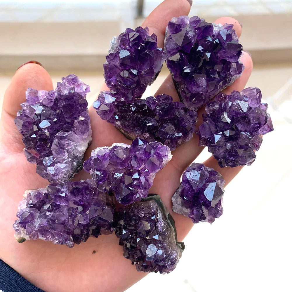Hand holding purple amethyst crystals against a neutral background