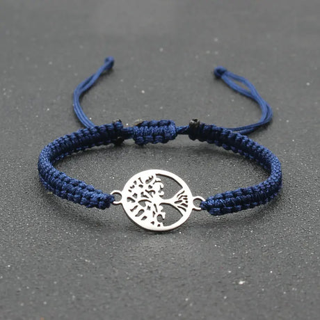 Navy blue braided bracelet with a silver tree of life charm on a dark gray background