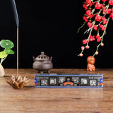 Incense stick box with incense burning, flowers, and a small statue on a wooden surface.