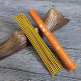 Incense sticks and an orange cylindrical container on a wooden surface