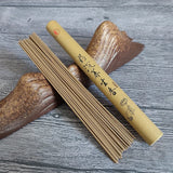 Incense sticks and their cylindrical packaging on a wooden surface