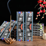 Incense sticks with decorative packaging on a wooden surface, with a dark background and floral elements.