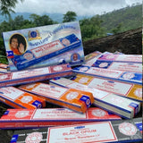 Collection of Nag Champa incense boxes with a scenic background