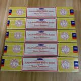 Multiple boxes of Nag Champa Californian White Sage incense on a wooden surface