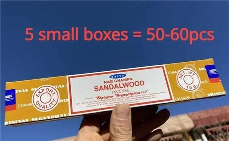 Nag Champa Sandalwood incense stick box held by a hand with text overlay on a blue sky background.