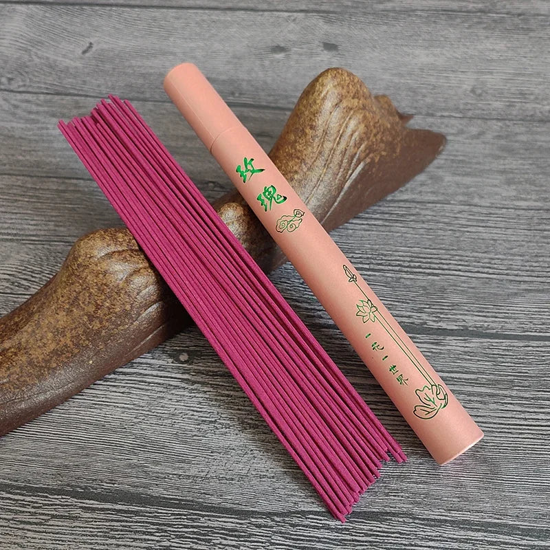 Pink incense sticks and a pink incense box with green text on a wooden surface