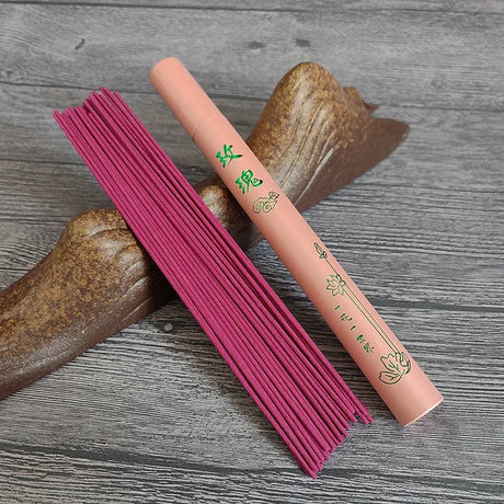 Pink incense sticks and a pink incense box with green text on a wooden surface