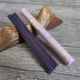 Purple incense stick holder with incense sticks on a wooden surface