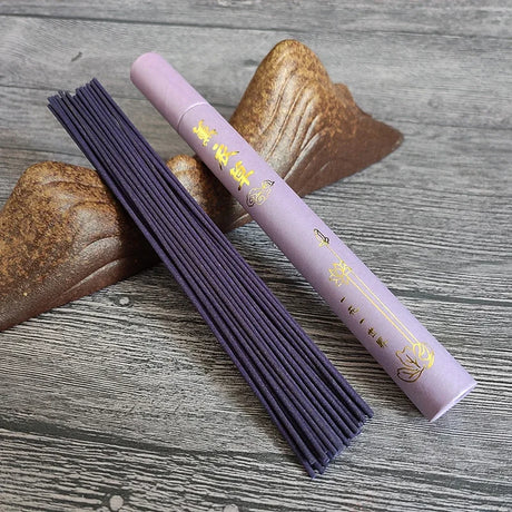 Purple incense stick holder with incense sticks on a wooden surface
