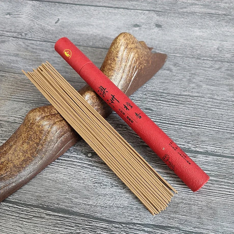 Red incense stick holder with incense sticks on a wooden surface
