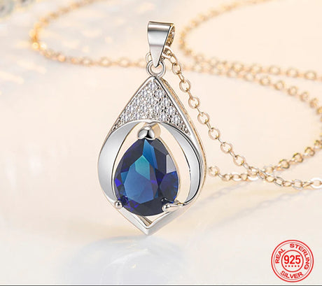 Silver pendant with blue gemstone on a gold chain, featuring ZDADAN branding.