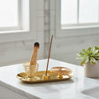 Gold incense burner with a single incense stick on a white background