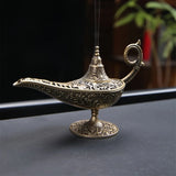 Decorative incense burner shaped like a genie lamp on a dark surface.