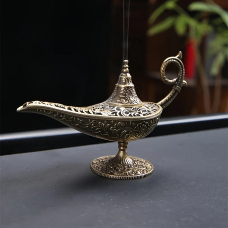 Decorative incense burner shaped like a genie lamp on a dark surface.