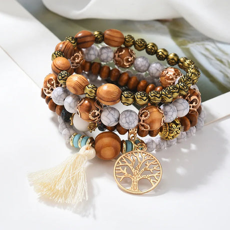 Stack of beaded bracelets with a tree of life charm on a white surface