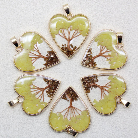 Five heart-shaped pendants with tree designs on a light gray background
