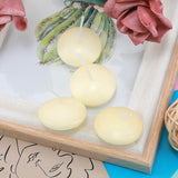 Four small round candles on a white surface with a cactus and pink flowers in the background.