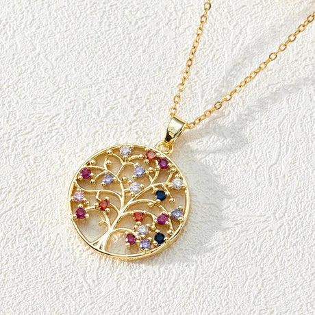 Gold necklace with a tree-shaped pendant featuring colorful gemstones on a light gray background