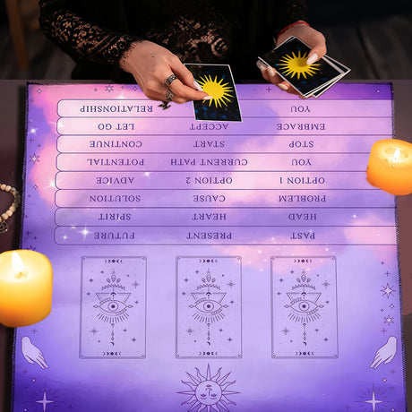Person holding tarot cards over a tarot reading mat with candles on either side.