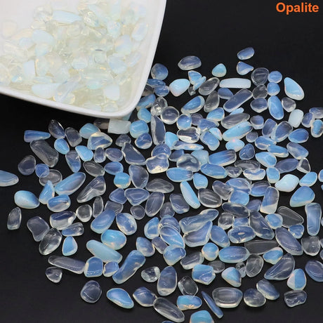 Opalite stones on a dark surface with a white container of opalite stones in the background.