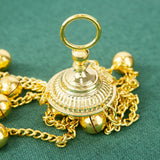 Gold bell with chain on a green fabric background